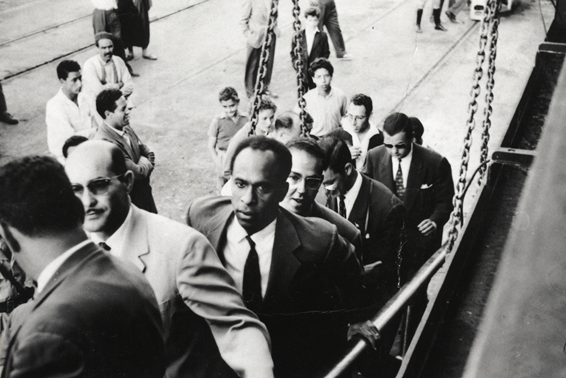 Frantz Fanon marchant sur une passerelle de navire. À la droite de Fanon se trouve Rheda Malek, un journaliste du journal du Front de libération nationale algérien El Moudjahid. Frantz Fanon Archives / IMEC